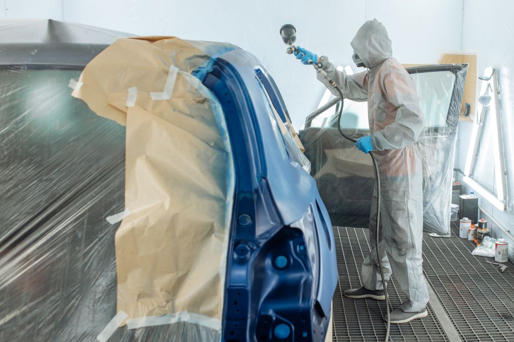 Carrossier ponçant un panneau de carrosserie dans un atelier au Québec